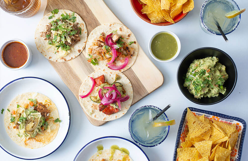 Sharing tacos with guacamole, salsas, tortilla chips and margaritas